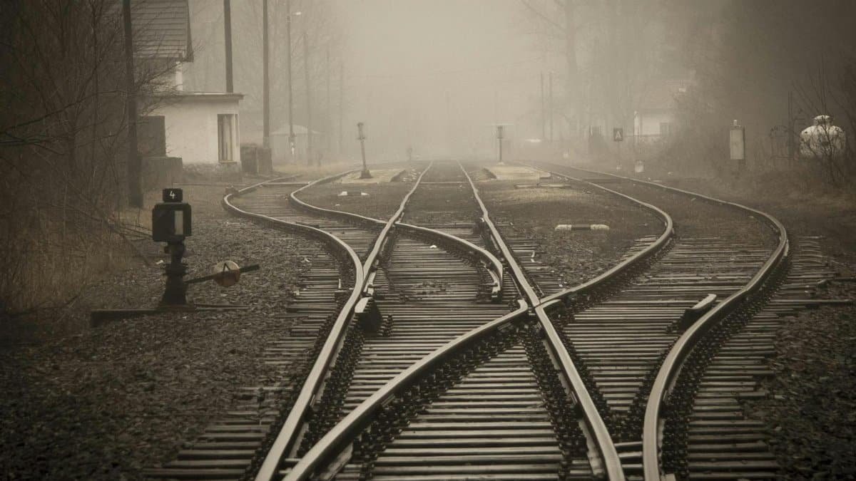 Moody foggy railway tracks in a misty landscape, evoking travel and mystery.