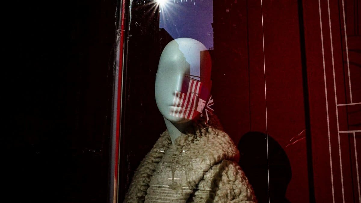 Mannequin in a New York City storefront with artistic reflection, showcasing fashion trends.