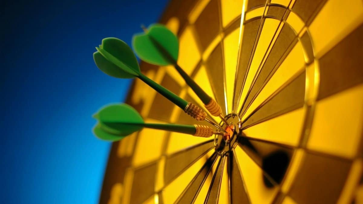 Close-up of darts hitting the bullseye on a dartboard symbolizing precision and success.