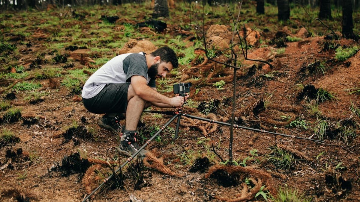 A man setting up equipment in a forest for environmental research.