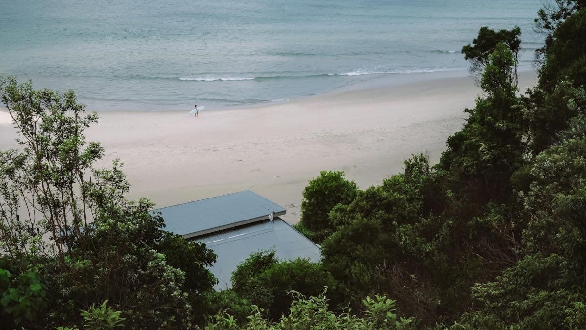 A serene view of Byron Bay beach with surrounding lush greenery and a peaceful ocean backdrop.