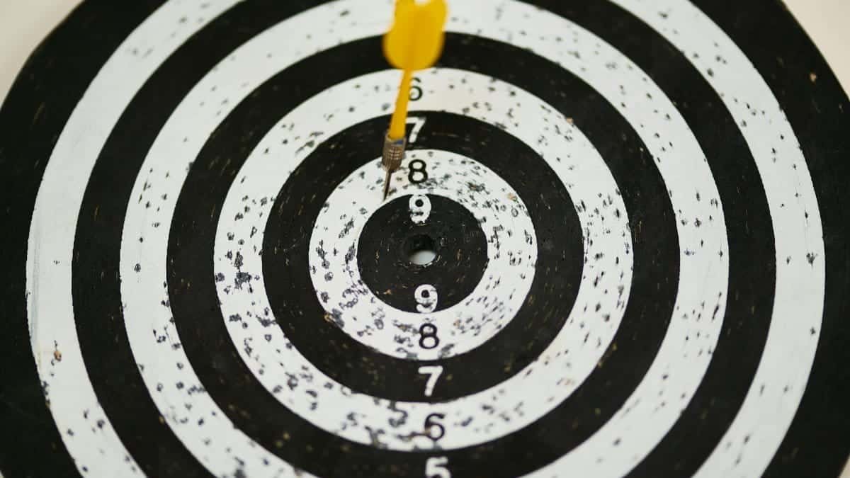Close-up of a dart hitting the bullseye on a black and white target board symbolizing success.