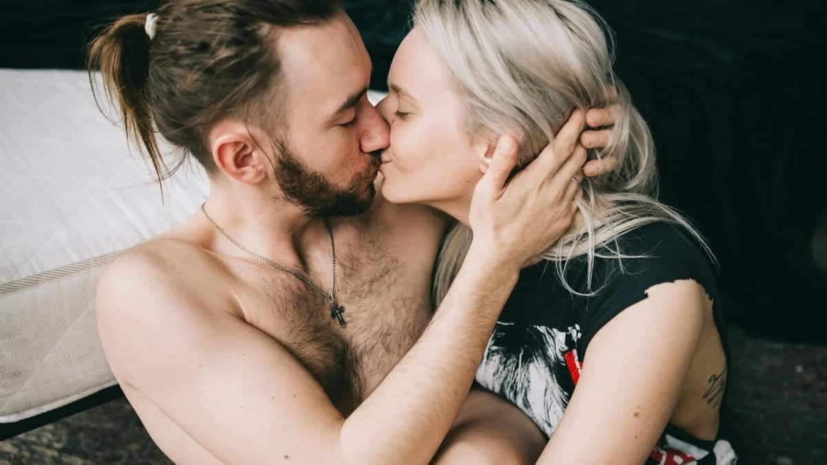 Romantic moment of an intimate couple kissing indoors, showcasing love and togetherness.