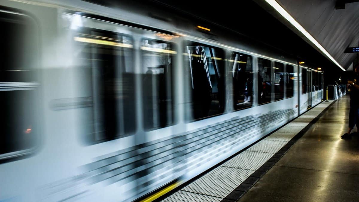 Blurred image of a modern train speeding through a dimly lit station platform.