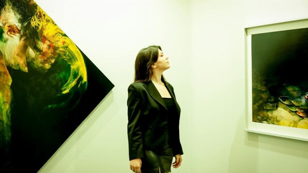 A woman in a black outfit admiring abstract paintings in a modern art gallery.