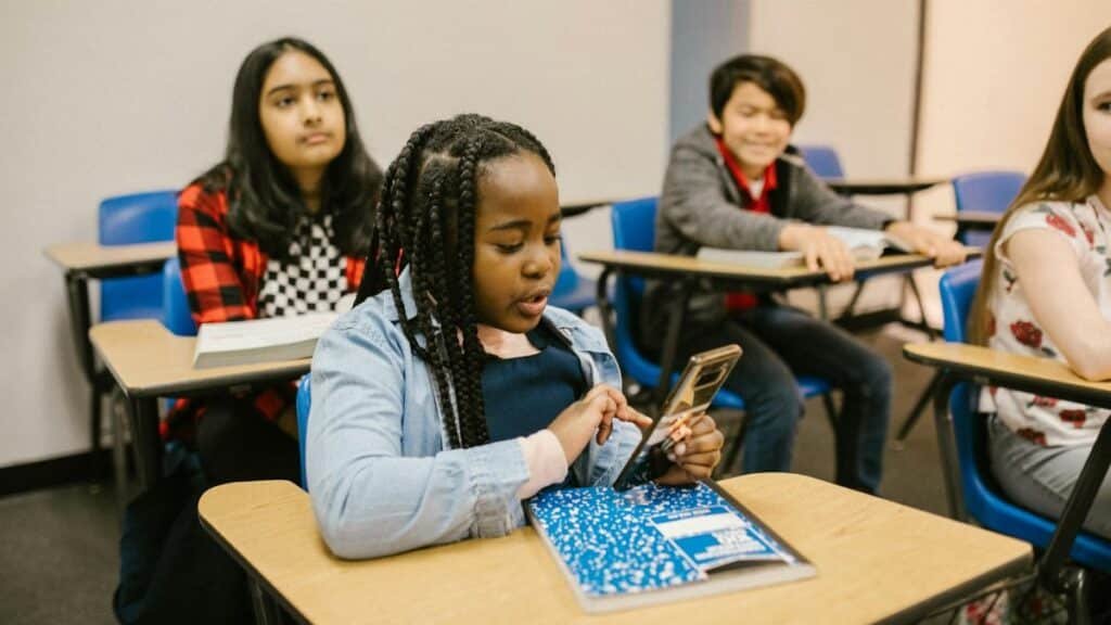 Students in a classroom using mobile phones, representing modern education.