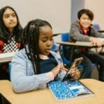 Students in a classroom using mobile phones, representing modern education.