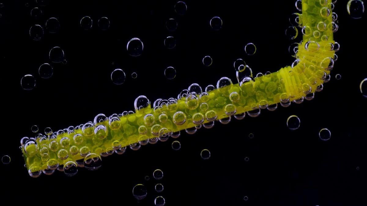 Close-up shot of a yellow straw submerged in liquid, covered with air bubbles.