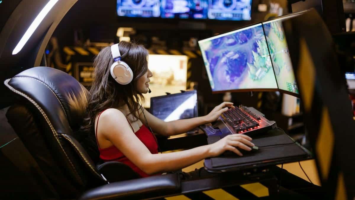 Young woman intensely focused on playing a multiplayer online game at a high-tech gaming station with a curved monitor.