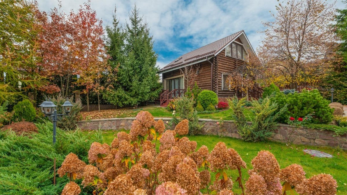 A picturesque log cabin surrounded by vibrant autumn foliage in a scenic garden setting.