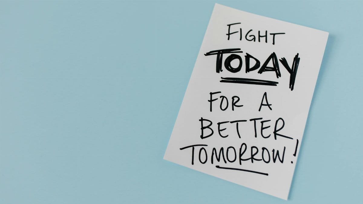 Inspirational handwritten message urging action for a better future on paper over a blue backdrop.
