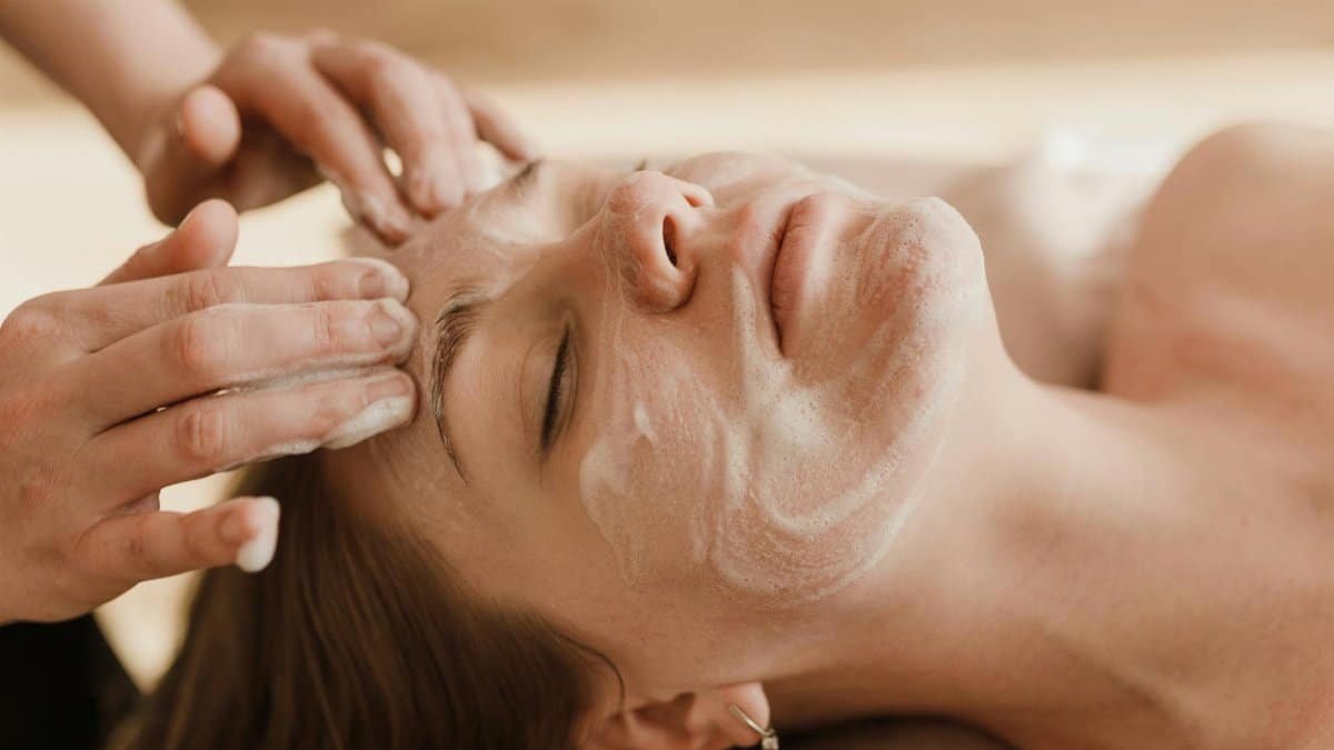 A close-up of a woman receiving a soothing facial massage with a skincare mask.