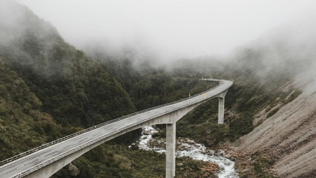 Scenic view of a bridge over a river in a foggy mountain landscape, capturing nature's beauty.