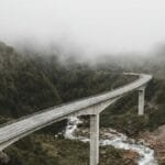 Scenic view of a bridge over a river in a foggy mountain landscape, capturing nature's beauty.