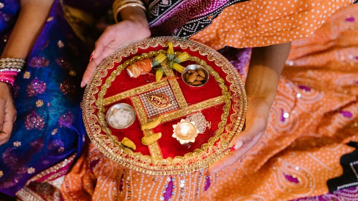 A vibrant festival plate with offerings held by a woman in traditional attire.