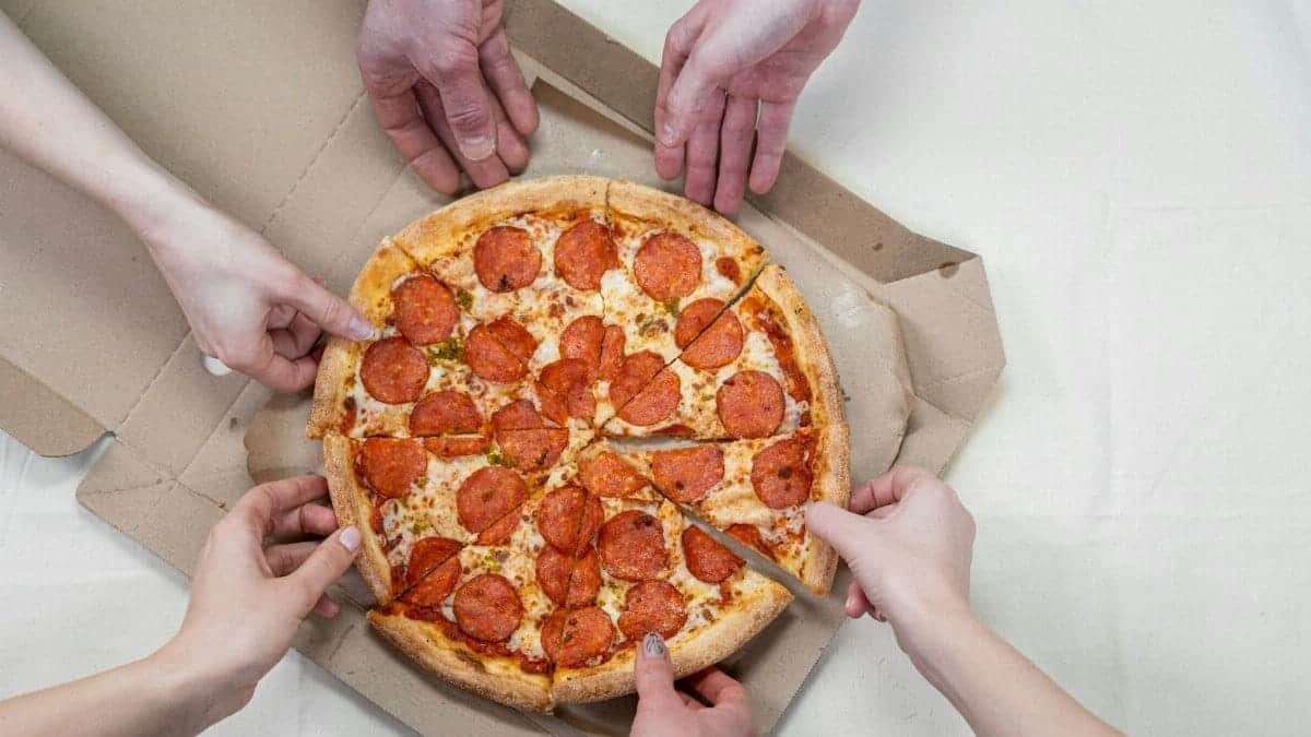 Group of friends sharing a delicious pepperoni pizza, perfect for social gatherings.