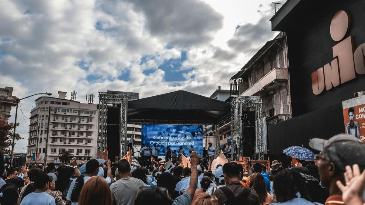 Large crowd gathered for a prayer event on an outdoor stage in the city.