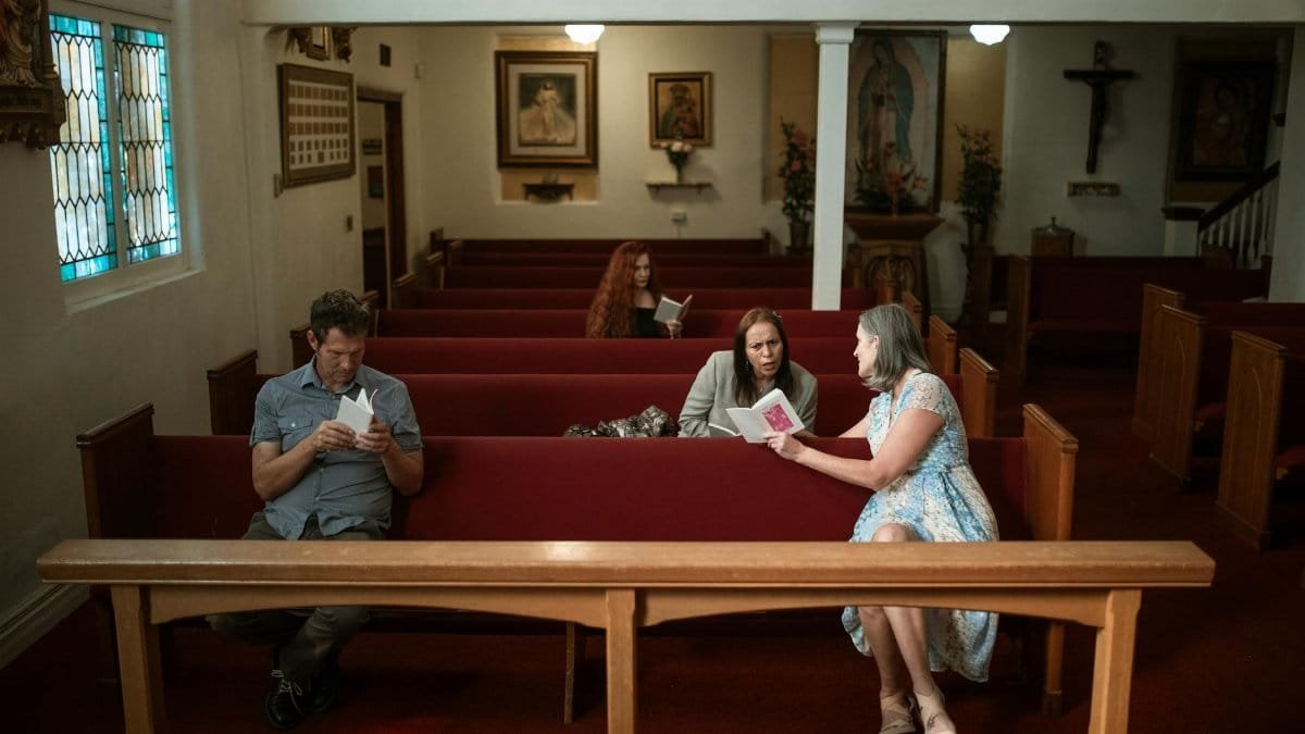 Interior view of a church with parishioners reading and conversing in pews, fostering a spiritual atmosphere.