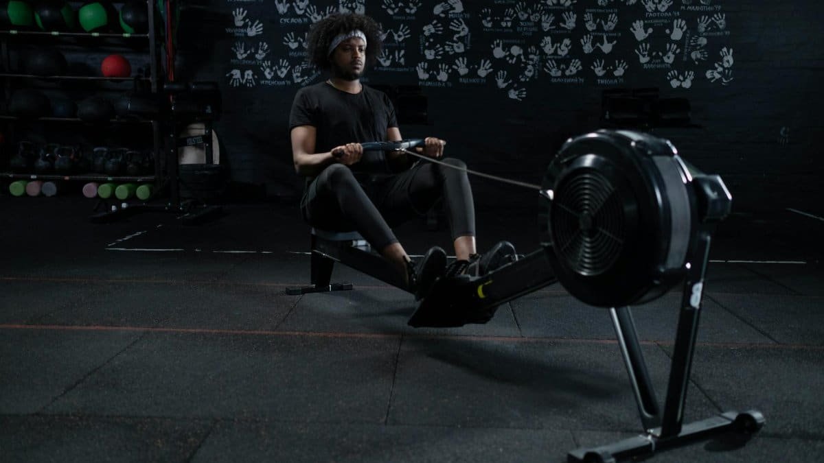 A man intensely working out on a rowing machine in a gym, promoting fitness and wellness.