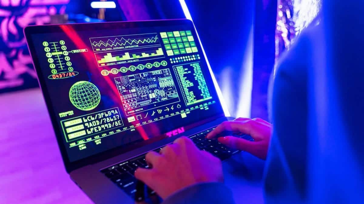 Person typing on a laptop with vibrant digital data display, highlighting cyber security.
