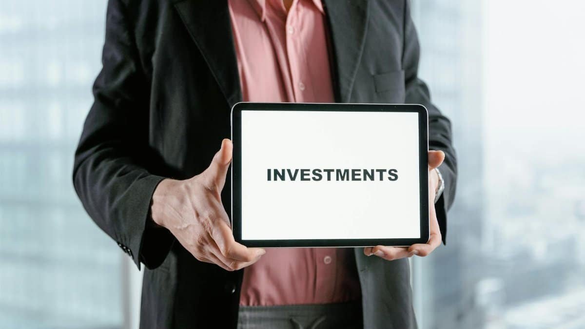 Professional holding a tablet with 'INVESTMENTS' text, ideal for finance and business themes.