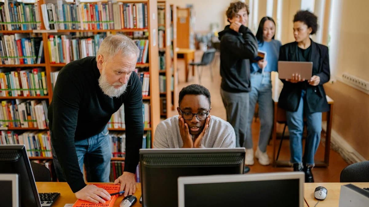 Students and a mentor collaborate in a university library, engaging in educational activities.