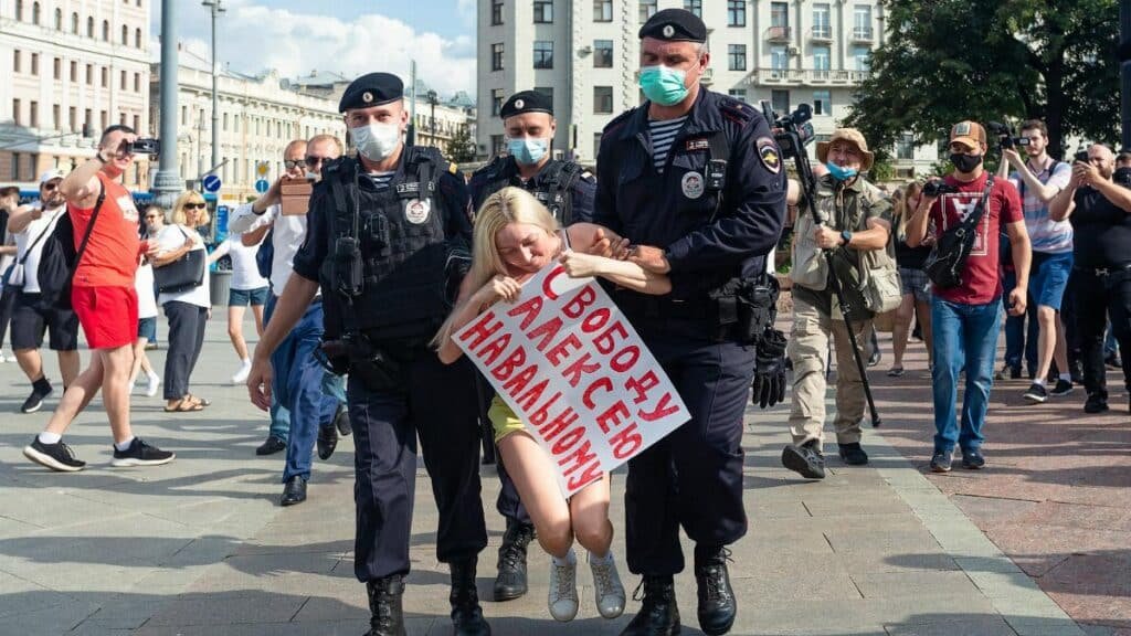 Protester being detained by police during an urban demonstration in broad daylight.