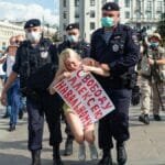Protester being detained by police during an urban demonstration in broad daylight.