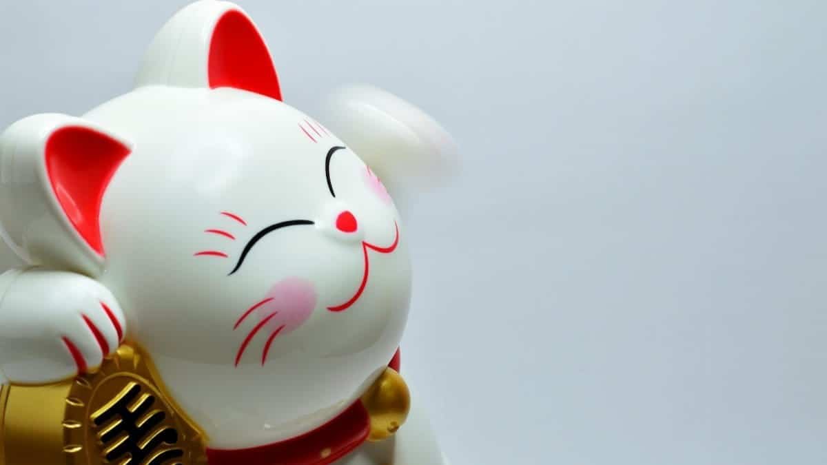Close-up of a white Maneki Neko figurine with a raised paw symbolizing luck and fortune.