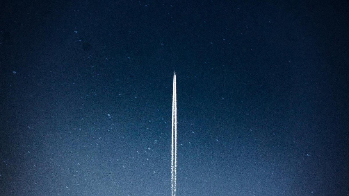 A rocket streaks through a starry night, leaving a trail in outer space.