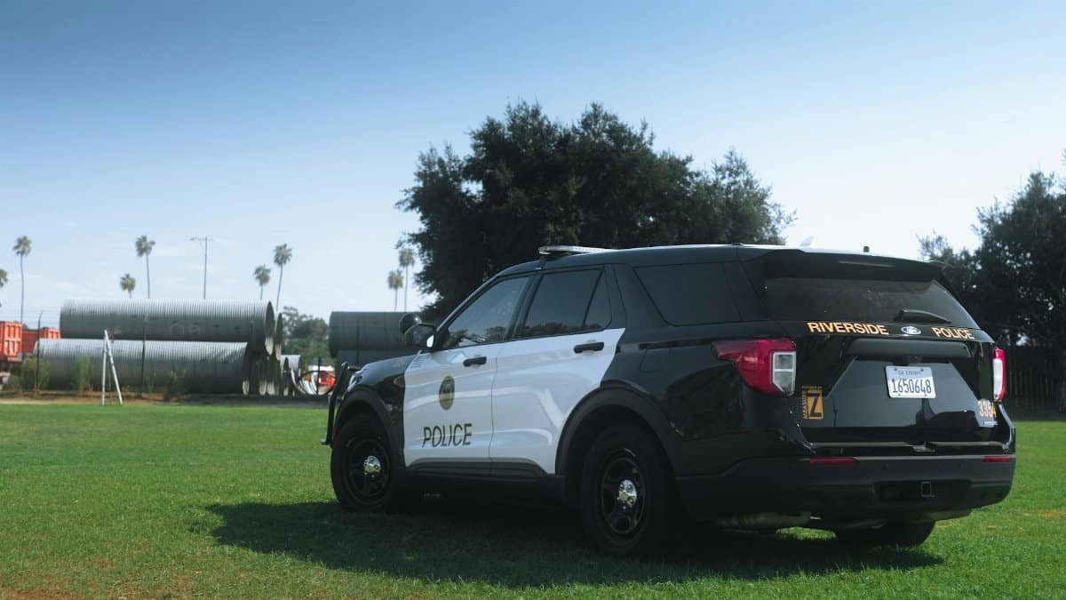 Black and white Riverside Police SUV parked in a sunny grassy area.