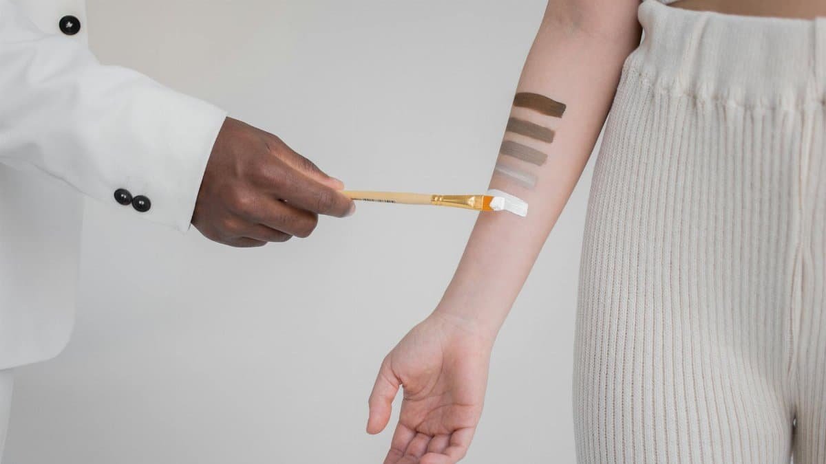 Detailed studio shot illustrating diverse skin tone testing using paint swatches on forearms.