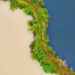 Aerial view of contrasting water bodies separated by lush green path in Banten, Indonesia.