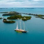 Stunning aerial view of a yacht sailing amidst the scenic islands and azure waters of Bermuda.