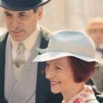 A smiling couple in vintage attire, enjoying a sunny day in New York.
