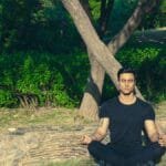 Man meditating peacefully in a lush Jaipur garden, embracing wellness and relaxation.