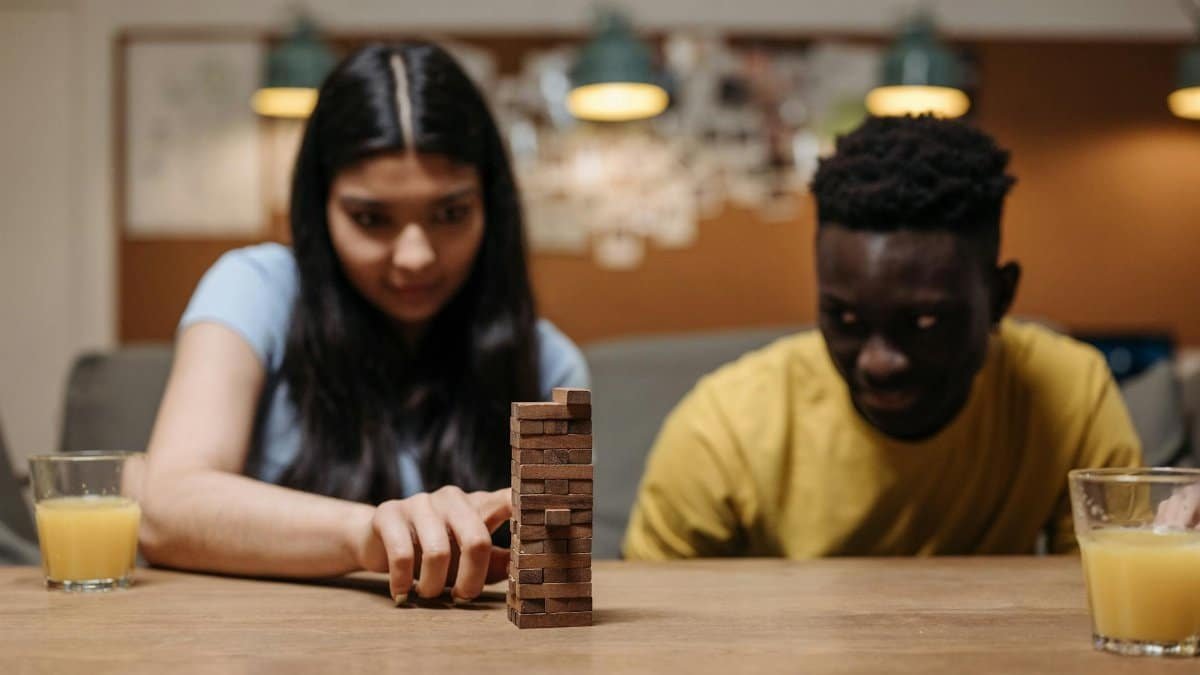 Two friends playing Jenga together indoors, focused and having fun.