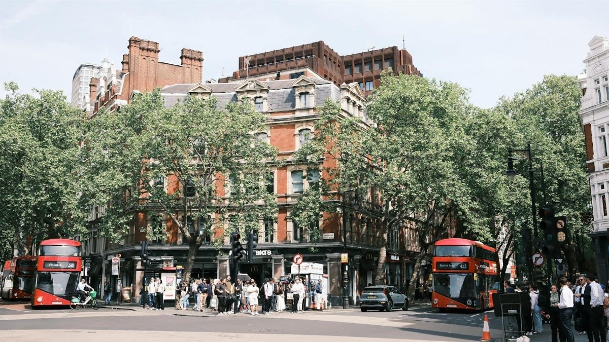 Lively street corner in London with iconic red double-decker buses and vibrant urban atmosphere.
