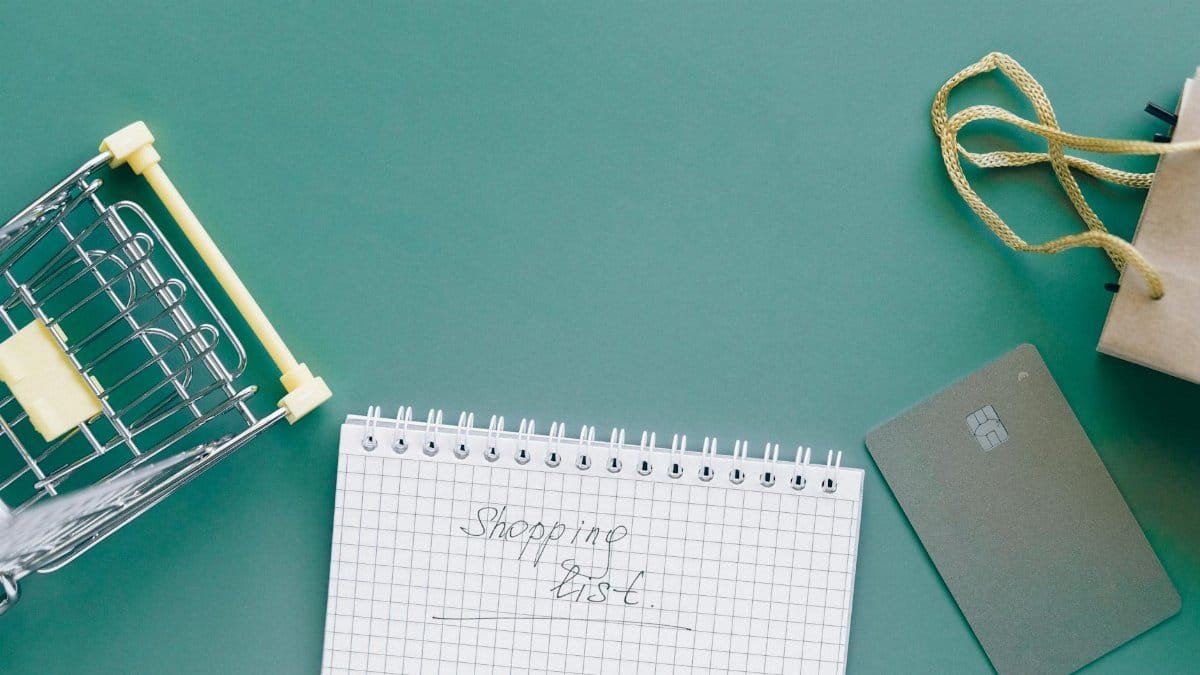 A top-down view of a shopping cart, list, card, and bag on a green background.
