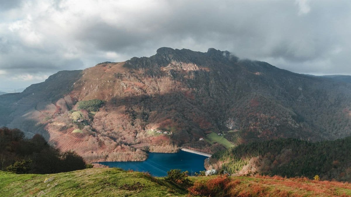 Majestic mountain scenery with a tranquil lake under clouded skies, offering natural beauty and serenity.