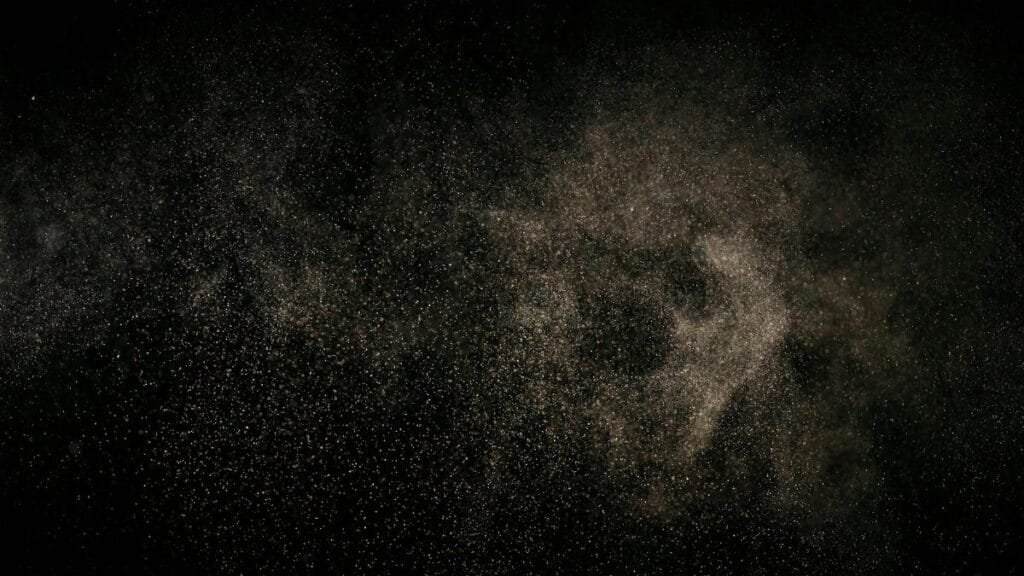 Abstract image of fine particles floating against a black background.