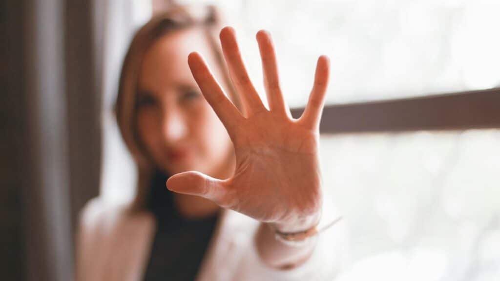 Close-up of a woman's hand gesturing stop with a blurred background indoors.
