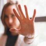 Close-up of a woman's hand gesturing stop with a blurred background indoors.