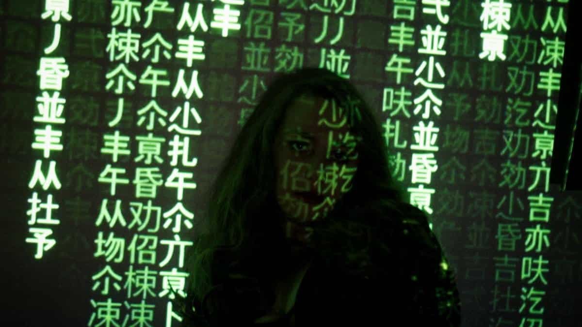 Silhouette of a woman with green code projected on her, depicting a tech and hacking theme.