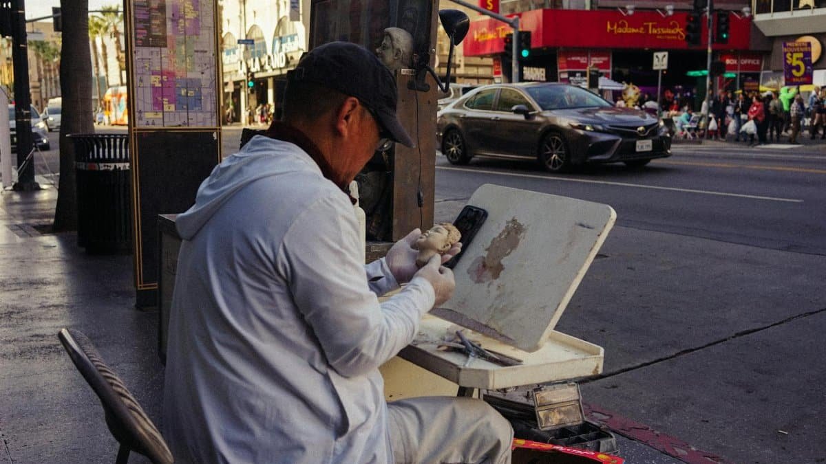 A street artist sculpting on Hollywood Boulevard, capturing lively urban scene.