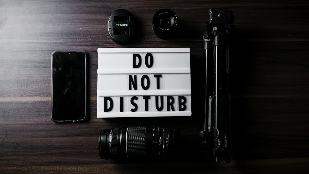 Flat lay of photography gear and a do not disturb sign on a table.