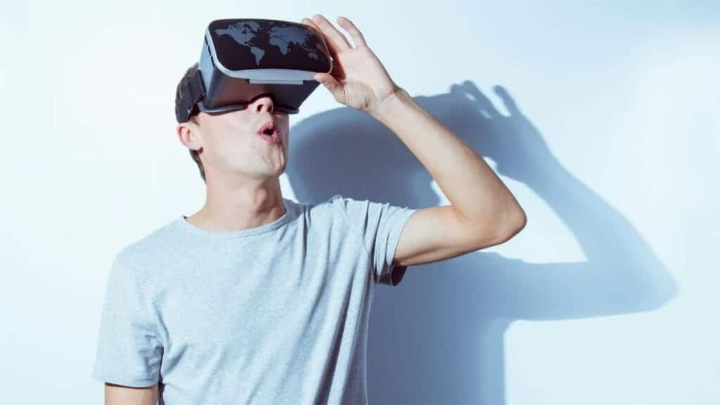 A young man immersed in virtual reality using a VR headset, expressing surprise.