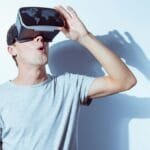 A young man immersed in virtual reality using a VR headset, expressing surprise.