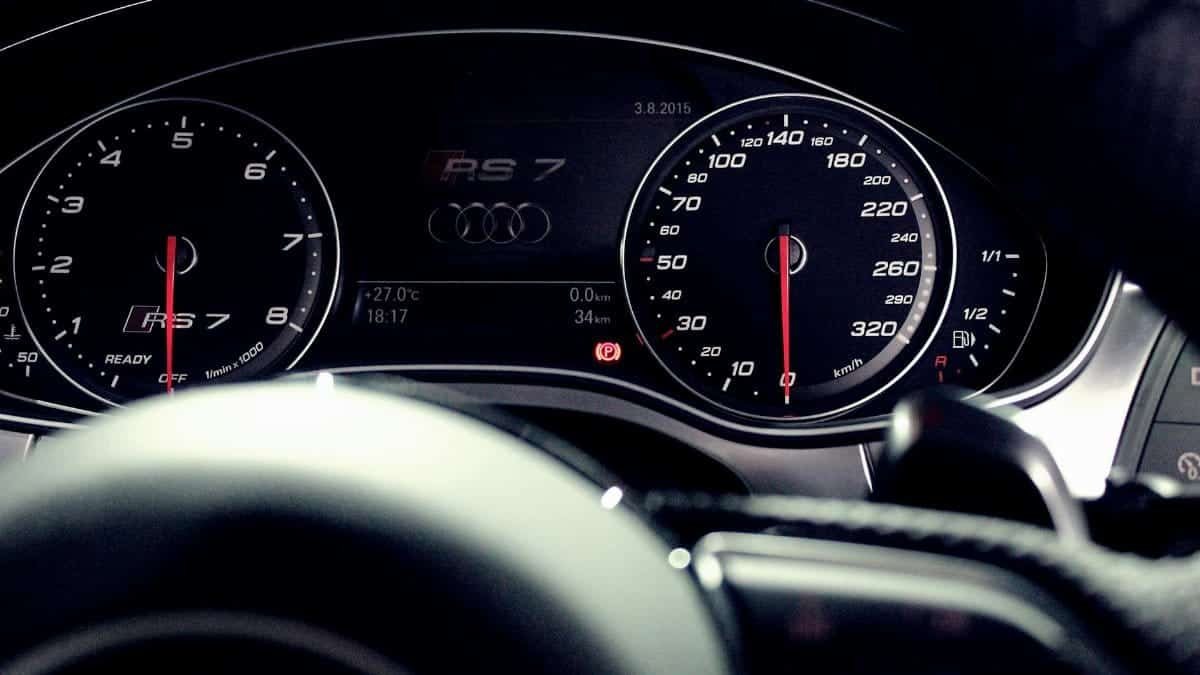 Close-up view of a luxury car dashboard featuring speedometer and gauges at night.