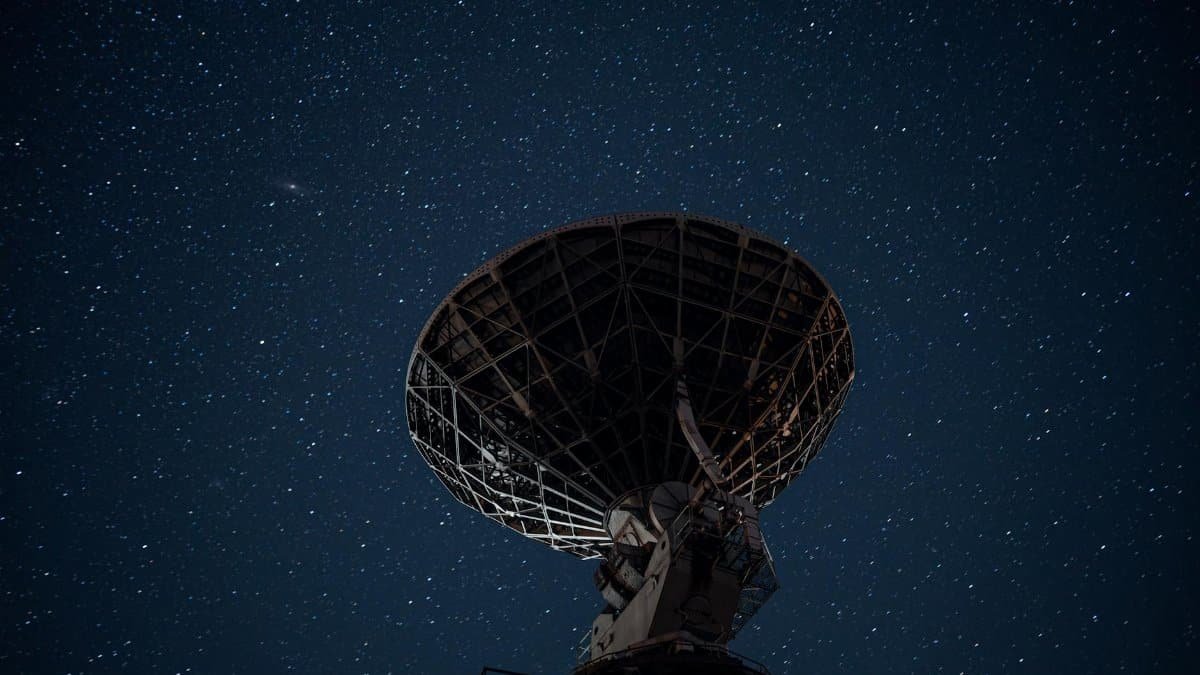 Silhouette of a satellite dish against a starry night sky, capturing cosmic exploration.